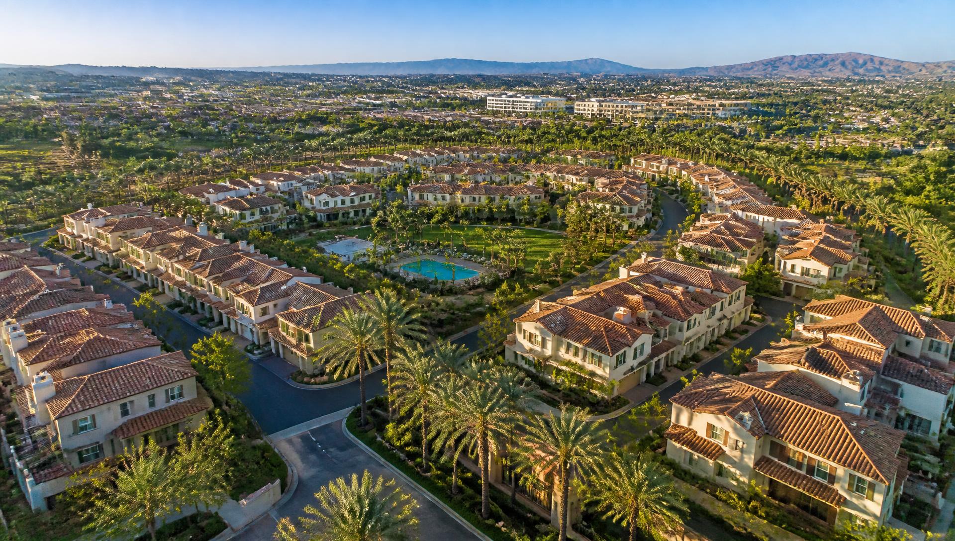 Aerial view of the gated Barcelona Private Estates community in Irvine, CA 92618, with tile-roof homes, private streets, and a neighborhood park and pool